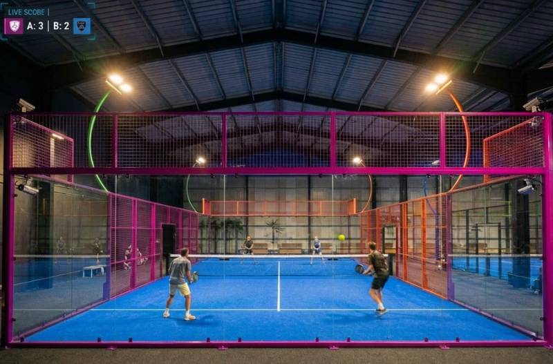 Échange entre quatre joueurs de padel niveau intermédiaire sur court indoor panoramique à Fos-sur-Mer